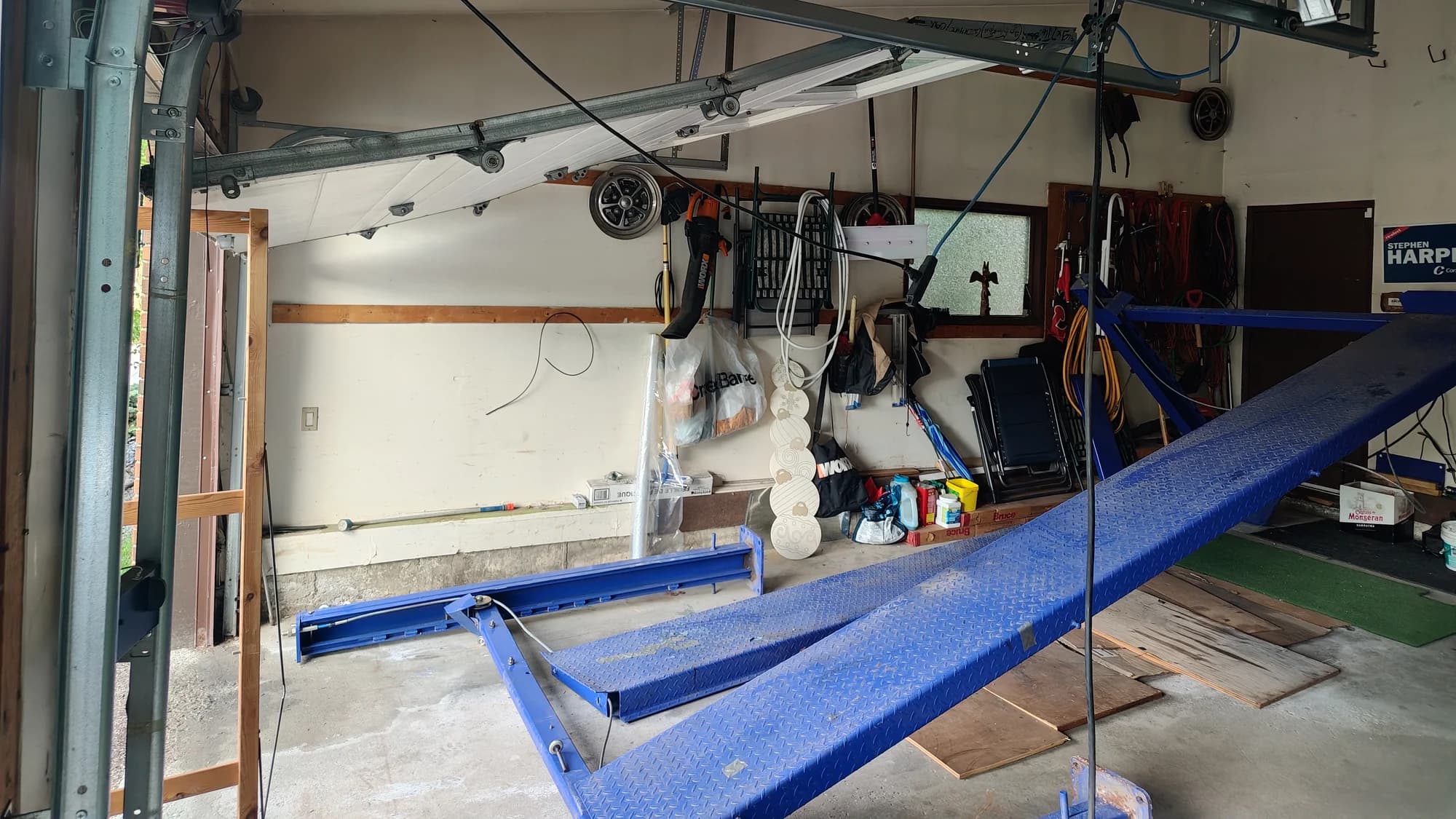 Off-track garage door hanging above a failed car lift inside a Canterbury Drive SW Calgary garage
