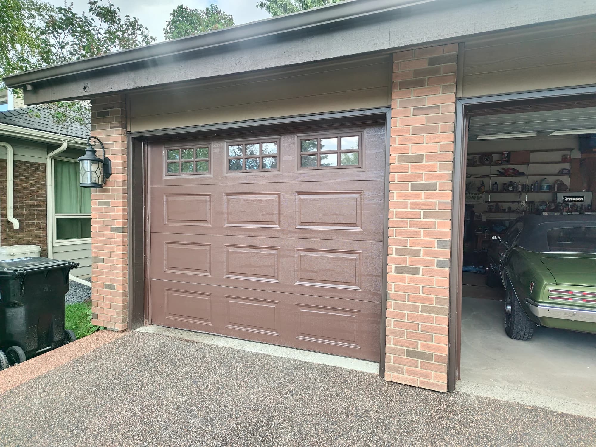 Repaired brown garage door on Canterbury Drive SW in Calgary after a car lift collapse knocked it off track