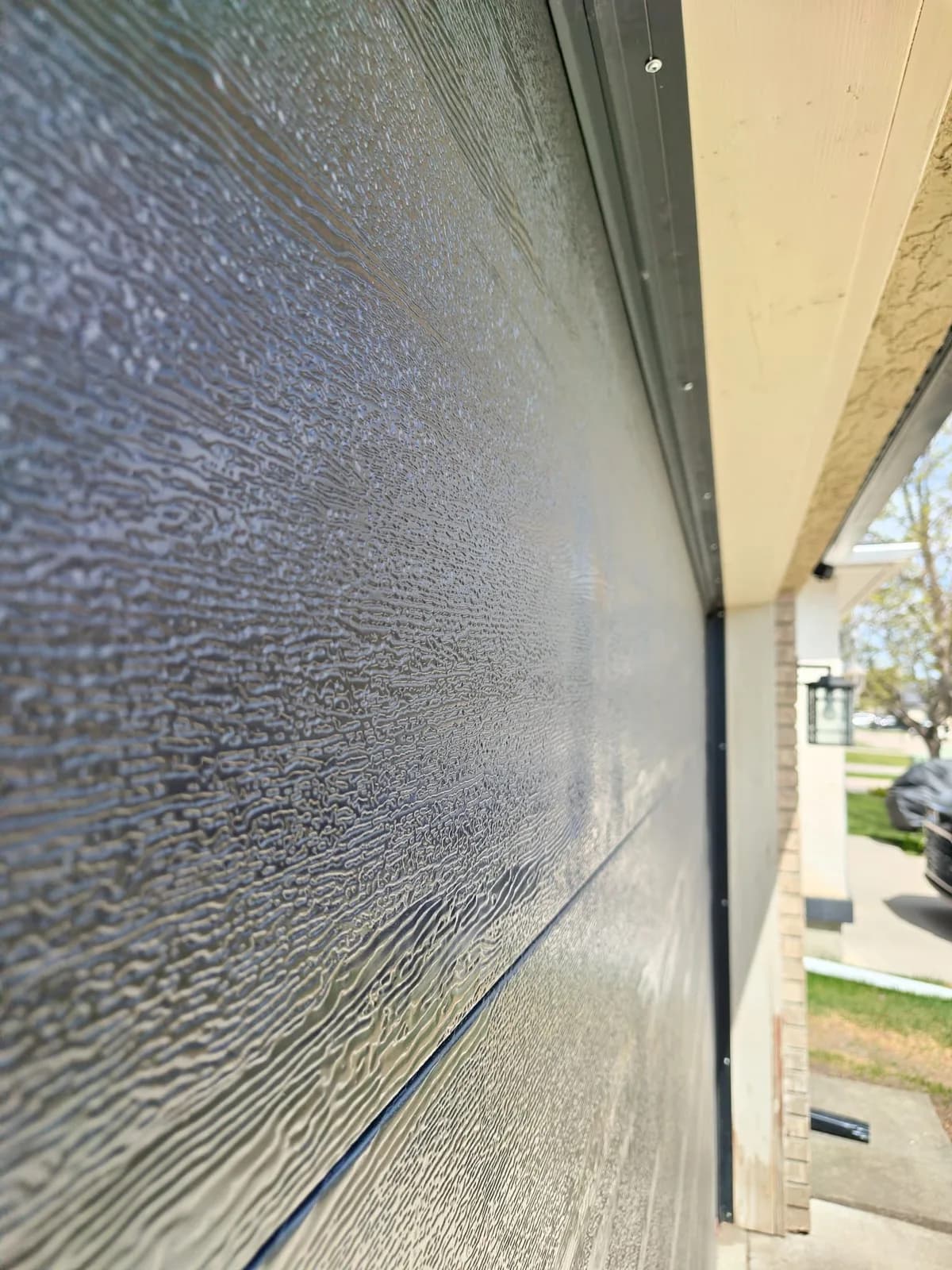 Close-up of bubbled woodgrain texture on a dark garage door panel