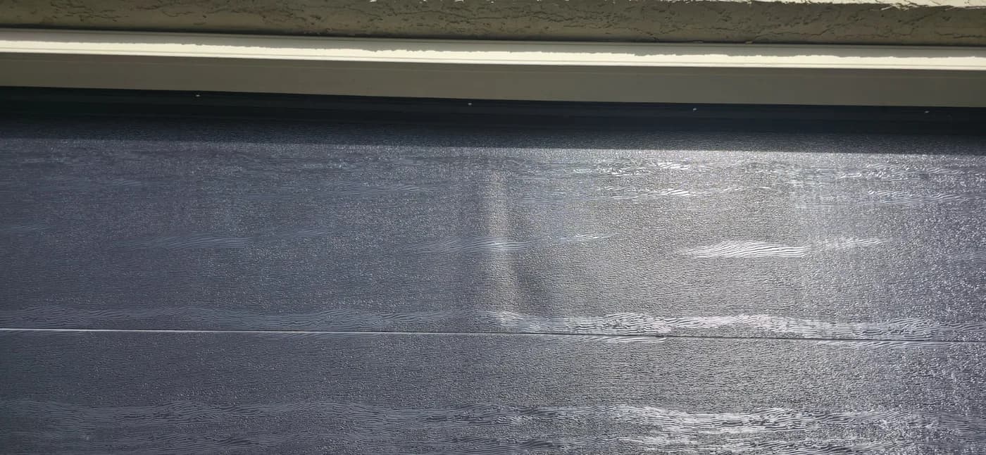 Dark Calgary garage door panel with heat-related surface bubbling