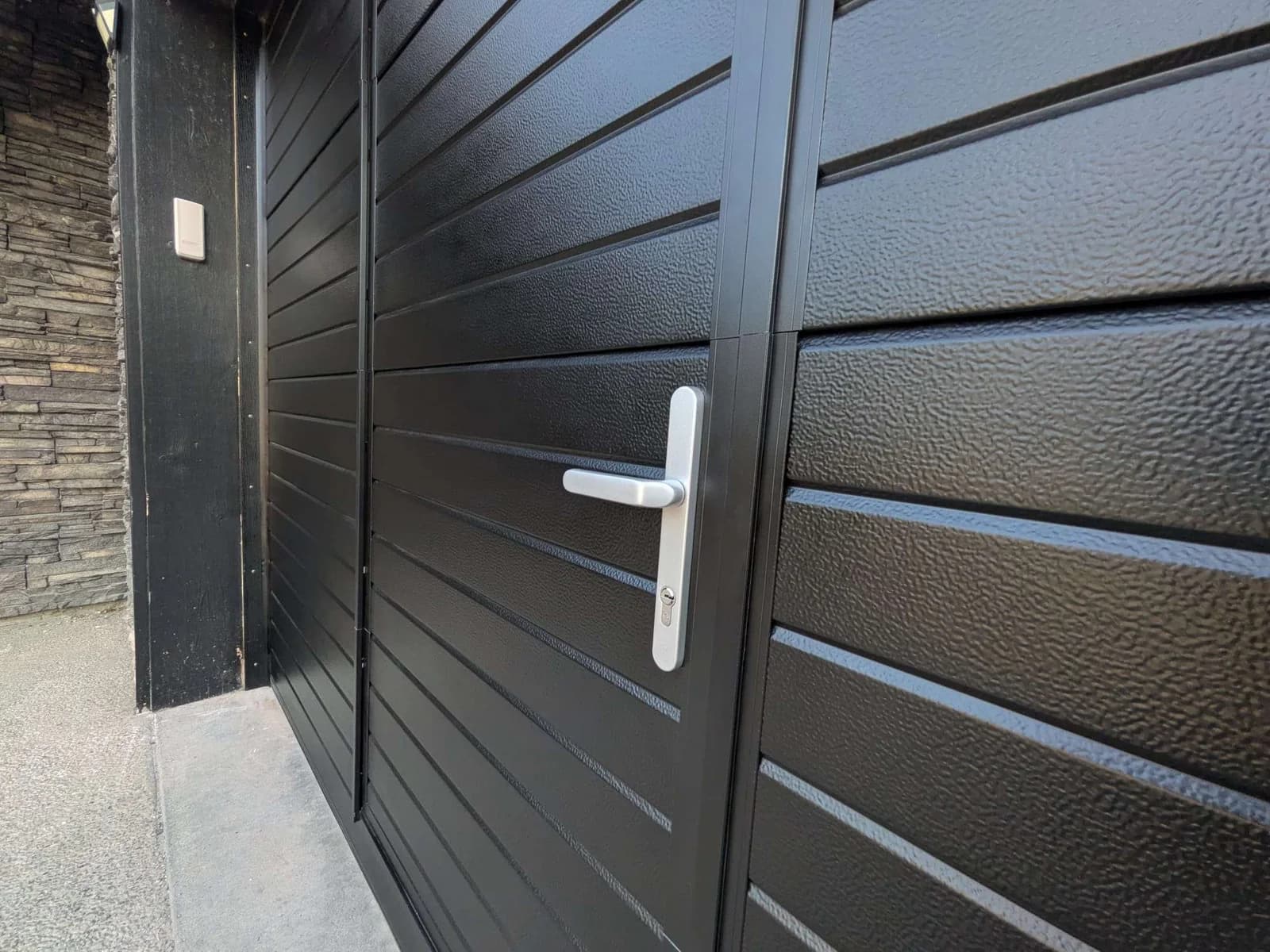 Close-up of the pedestrian handle lock and Ribbed panel texture on a Ryterna garage door