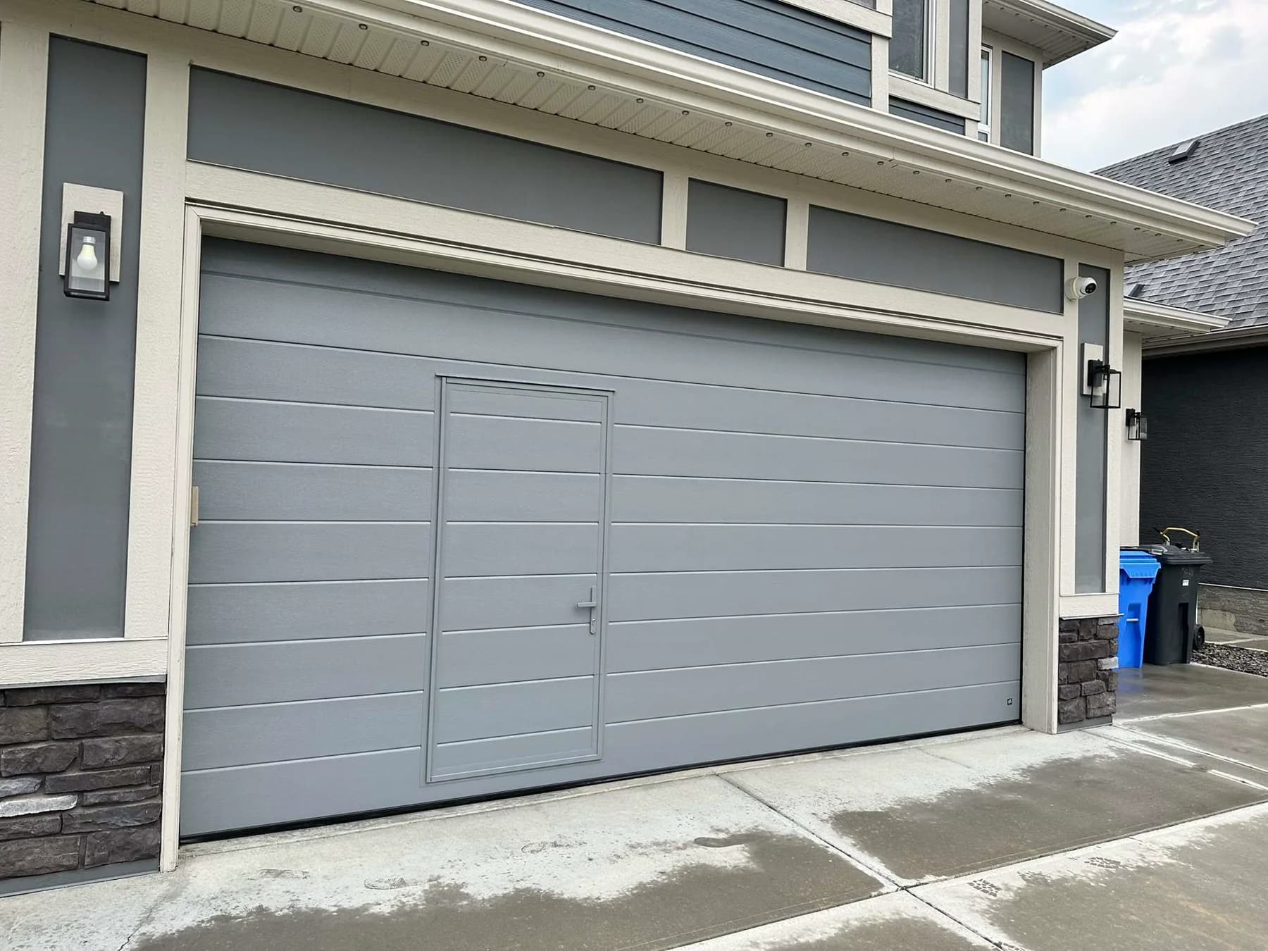 Angled exterior view of a Ryterna garage door with integrated pedestrian door in Mahogany Calgary