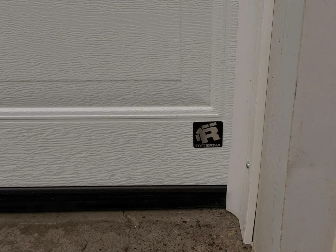 Ryterna badge on a white Cassette woodgrain garage door panel